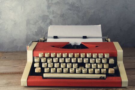 Old red typewriter on the table near the wallの写真素材