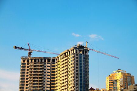 Industrial crane near the building against the blue sky. Construction site.の写真素材