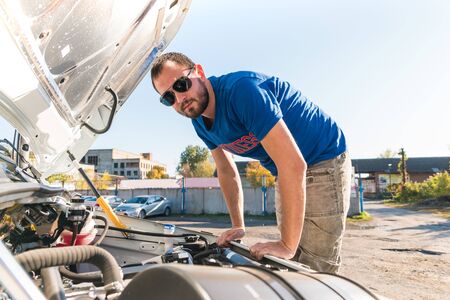 A man driver is repairing a truck with an open hood.の写真素材