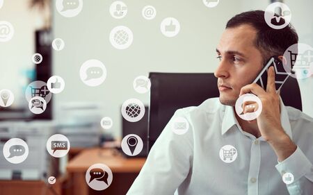 Closeup portrait of a young man working with a phone with a laptop holding a mouse in his hands....