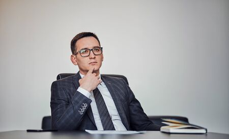 Closeup portrait of a young businessman sitting at a computer desk in a modern officeの写真素材