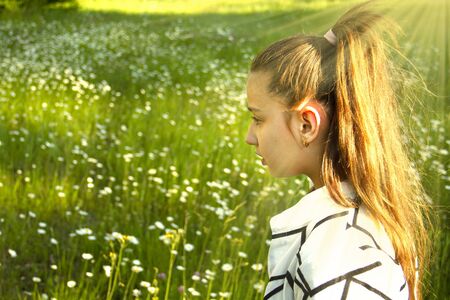 Beautiful little smiling girl in a field of daisies. Childhood concept. Cute baby in a field of blooming daisies in summer. Wildflowers.の写真素材