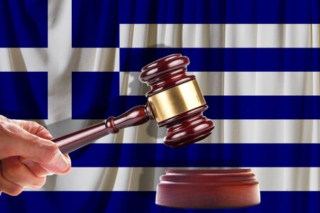 Judge wooden gavel on the background of the flag of Greece. Oil and gas industry. The concept of oil fields and oil companies.の写真素材