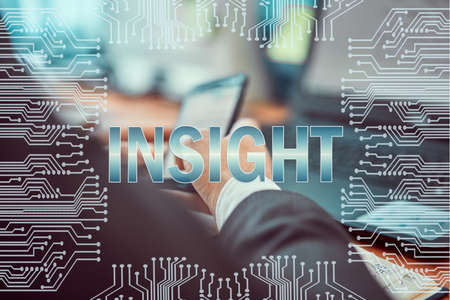 Circuit board on the background of a man working on a laptop and holding a smartphone in his hands. Caption: INSIGHTの写真素材