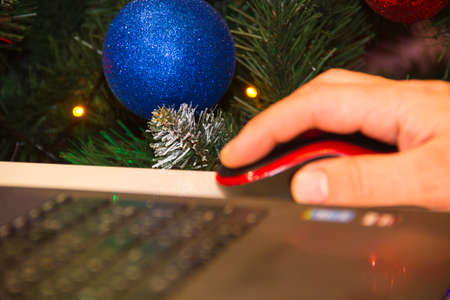Christmas tree with toys near the laptop. Online shopping for gifts, laptop with Christmas lights...