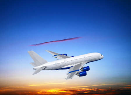Commercial white plane airliner flying above dramatic clouds in beautiful sunset light. Travel concept.の写真素材