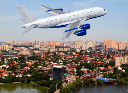 Commercial white plane airliner flying over the city. Travel concept.の写真素材