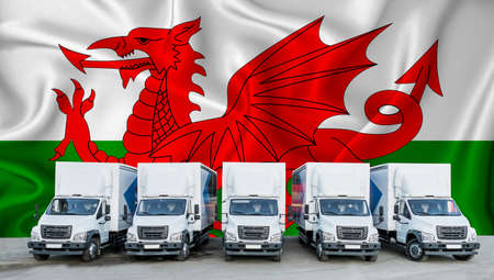Wales flag in the background. Five new white trucks are parked in the parking lot. Truck, transport, freight transport. Freight and logistics conceptの写真素材