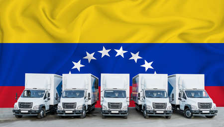 Venezuela flag in the background. Five new white trucks are parked in the parking lot. Truck, transport, freight transport. Freight and logistics conceptの写真素材