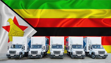 Zimbabwe flag in the background. Five new white trucks are parked in the parking lot. Truck, transport, freight transport. Freight and logistics conceptの写真素材