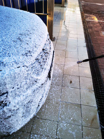 A young man at a car wash washes the car under high pressure. Selective focus.の写真素材