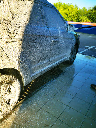 A young man at a car wash washes the car under high pressure. Selective focus.の写真素材