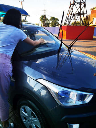 A young girl at a car wash, washes the car using a microfiber cloth. Selective focus.の写真素材