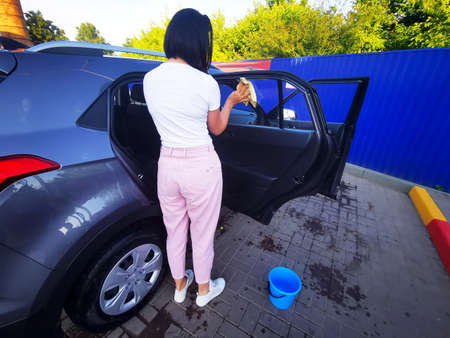 A young girl at a car wash, washes the car using a microfiber cloth. Selective focus.の写真素材