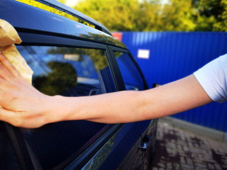A young girl at a car wash, washes the car using a microfiber cloth. Selective focus.の写真素材