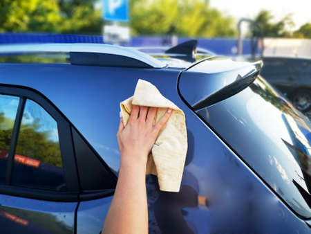 A young girl at a car wash, washes the car using a microfiber cloth. Selective focus.の写真素材