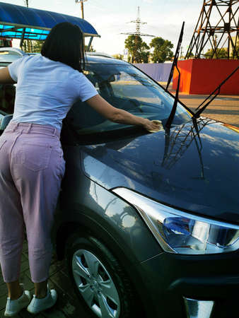 A young girl at a car wash, washes the car using a microfiber cloth. Selective focus.の写真素材