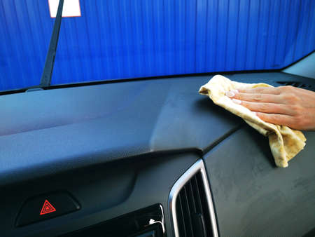 A young girl at a car wash, washes the car using a microfiber cloth. Selective focus.