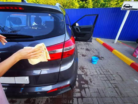 A young girl at a car wash, washes the car using a microfiber cloth. Selective focus.の写真素材