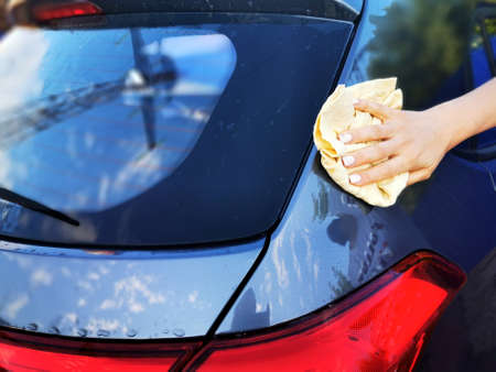 A young girl at a car wash, washes the car using a microfiber cloth. Selective focus.の写真素材