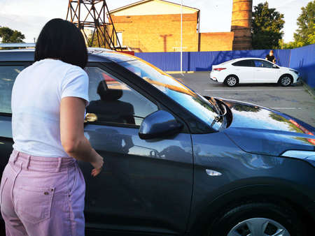 A young girl at a car wash, washes the car using a microfiber cloth. Selective focus.の写真素材