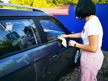 A young girl at a car wash, washes the car using a microfiber cloth. Selective focus.の写真素材