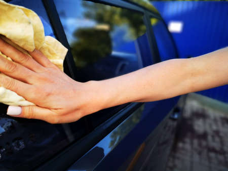 A young girl at a car wash, washes the car using a microfiber cloth. Selective focus.の写真素材