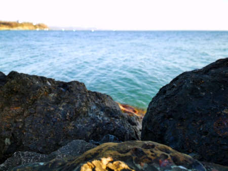 pebbles by the sea. Silky blue sea waves from long exposure. Stones on the Black Sea coast in cloudy weather against the background of the gray sea and sky in the Krasnodar Territoryの写真素材