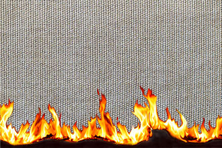Curled edge of light fabric and burnt, curled against a black background. Blazing flames. Fire....
