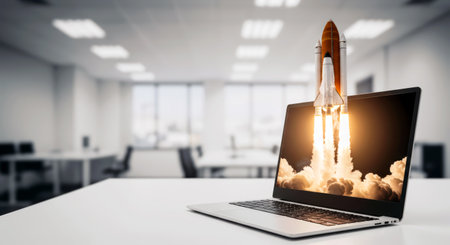Space Rocket Launch From Laptop Screen, With Blurred Office In The Background. Creative digital startup concept.の素材