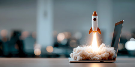Space Rocket Launch From Laptop Screen, With Blurred Office In The Background. Creative digital startup concept.の素材