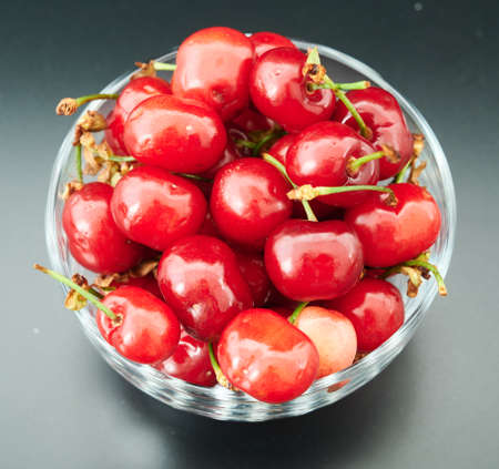 fresh cherries in a glass plate on a shady backgroundの写真素材