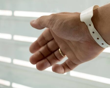 Male hand with newborn hospital birth identification wrist tag. New father after baby birth. New...