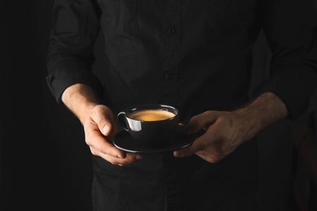 A Cup of coffee in the hands of men, dark backgroundの写真素材