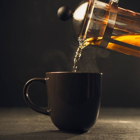 The process of pouring black tea into a Cup,dark background, hot drinkの写真素材