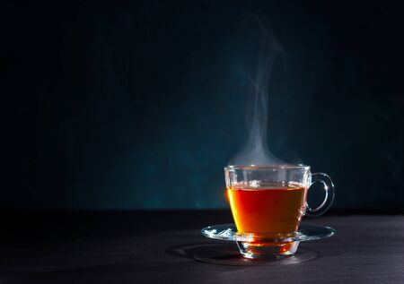 Freshly brewed black tea in a transparent glass Cup,escaping steam,darker background.の写真素材