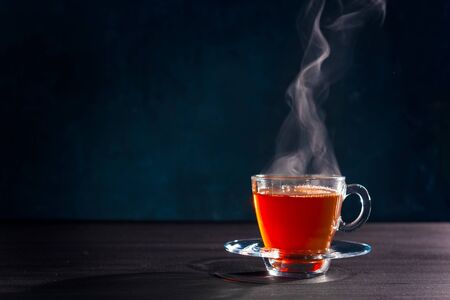 Freshly brewed black tea in a transparent glass Cup,escaping steam,darker background.の写真素材