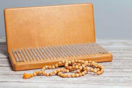 Tibetan Buddhist rosary, called mala or japamala. Brown Sadhu wooden boards with nails for yoga and spiritual practices on the gray background. The concept of meditation, standing on nails, therapy.の写真素材