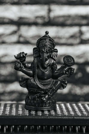 Stone statue of Lord Ganesha, hindu God. Close-up black Sadhu wooden boards with nails for yoga, spiritual practices on the gray background and dark brick wall.の写真素材