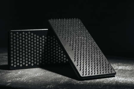 Close-up black Sadhu wooden boards with nails for yoga on gray background and dark brick wall.