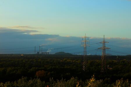 Two electrical line towers and a power plant in a woody areaの写真素材