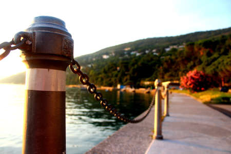 Seafront promenade at the Mediterranean sea before sunset with a chained fence