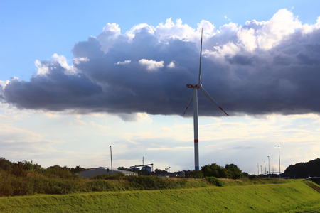 A wind turbine in a peaceful landscape with green grass, blue skye and a riverの写真素材