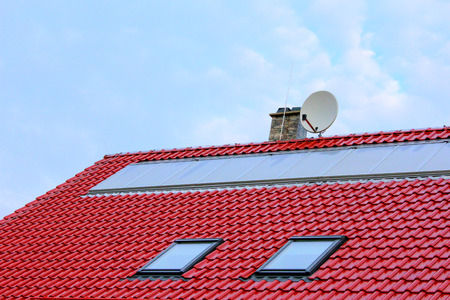 Large flat solar collectors on a red roofの写真素材