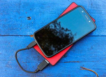 Smartphone and powerbank on a blue boardの写真素材