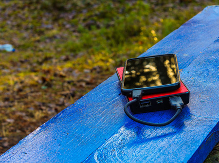 Smartphone and powerbank on a blue boardの写真素材