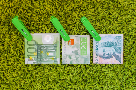 Three green banknotes 100 euro 100 swedish crownes and 200 swedish crownes in green clothes pegs at...