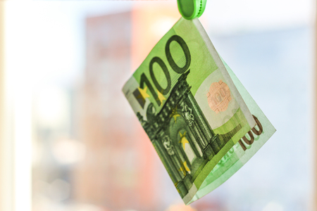 Green banknote 100 euro in a green clothes pegの写真素材