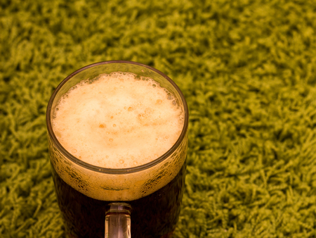 Glass of dark brown beer on green carpet backgroundの写真素材