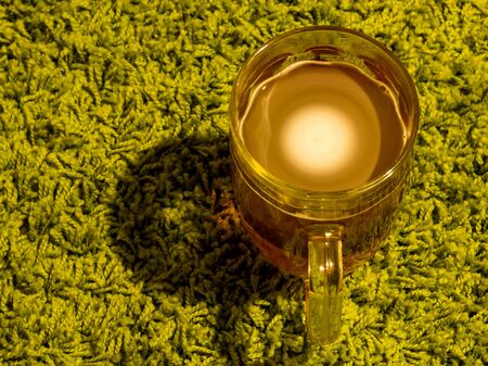 Glass of light beer with white foam whirlwind on green carpet backgroundの写真素材